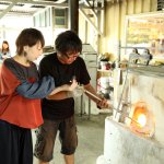 「吹きガラス簡単コース」 1.1300℃にもなる窯の中で溶けたガラスをすくいとる。