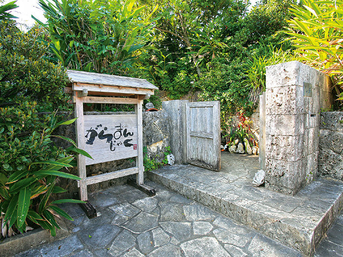 在樹木圍繞的寬敞庭院裡，紅磚瓦屋頂呈現出沖繩的古早氣氛